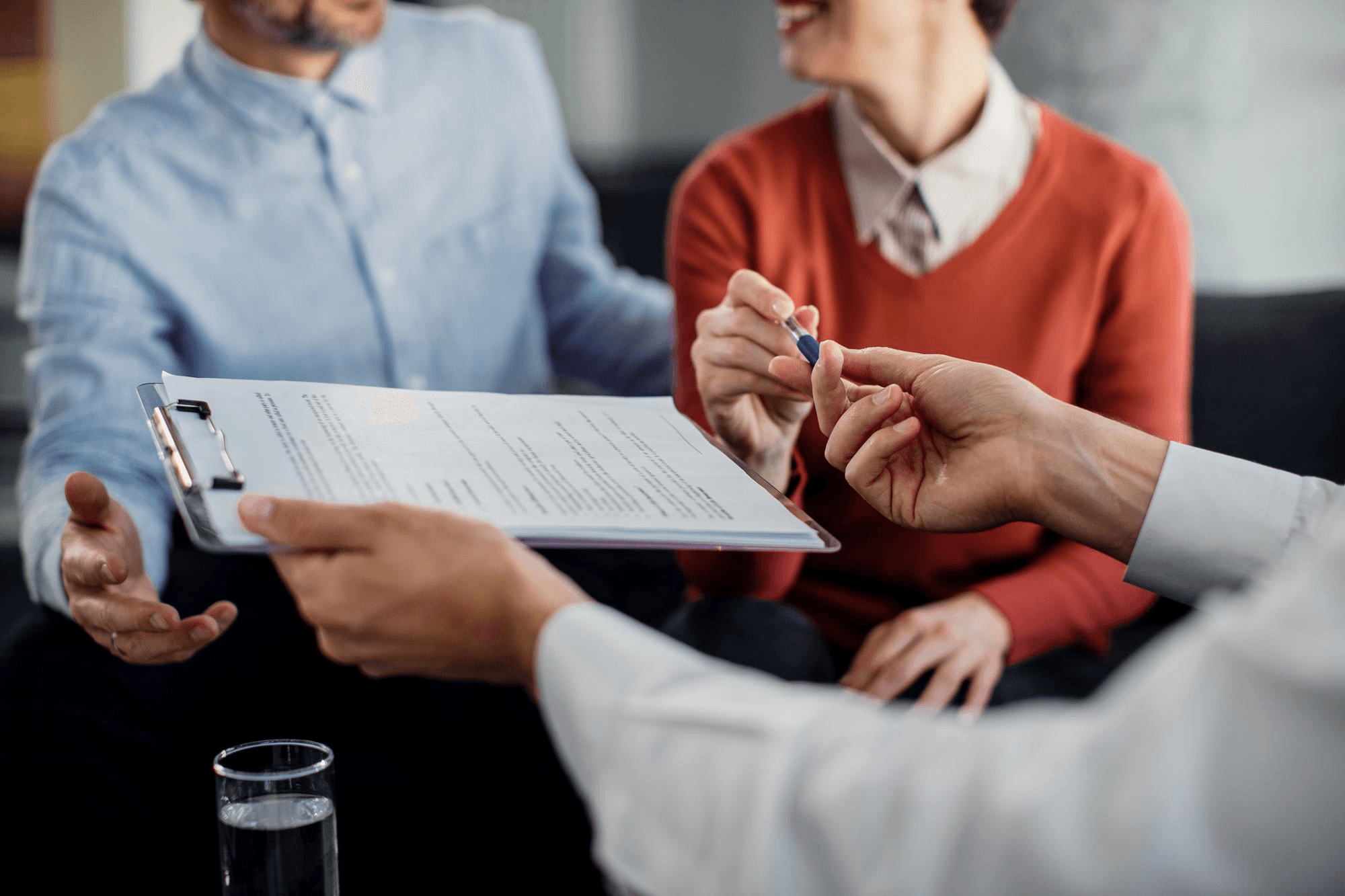 Man and woman about to sign life insurance documents while reviewing existing policies..