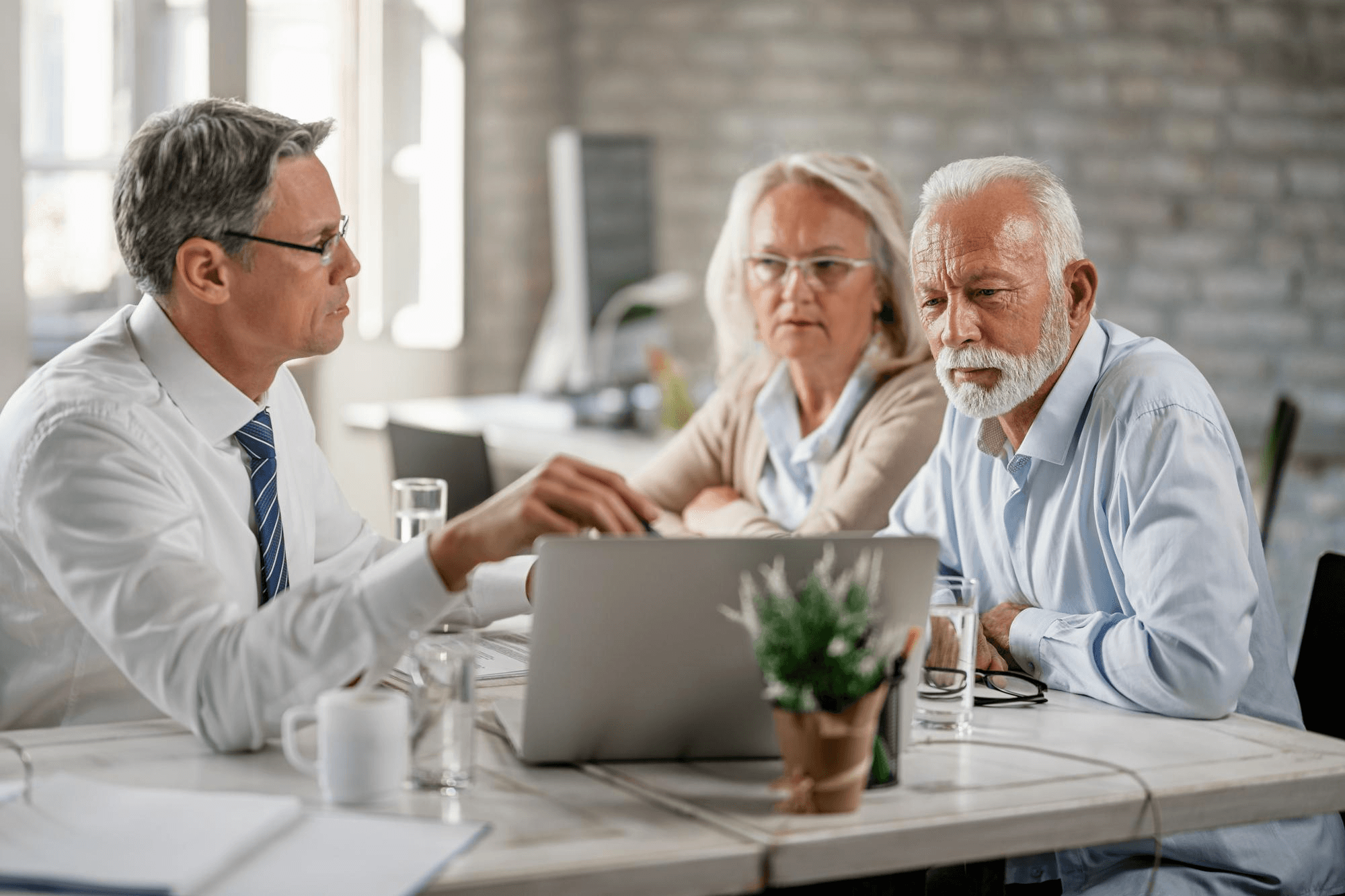 Man explaining retirement insurance plans to elderly couple.