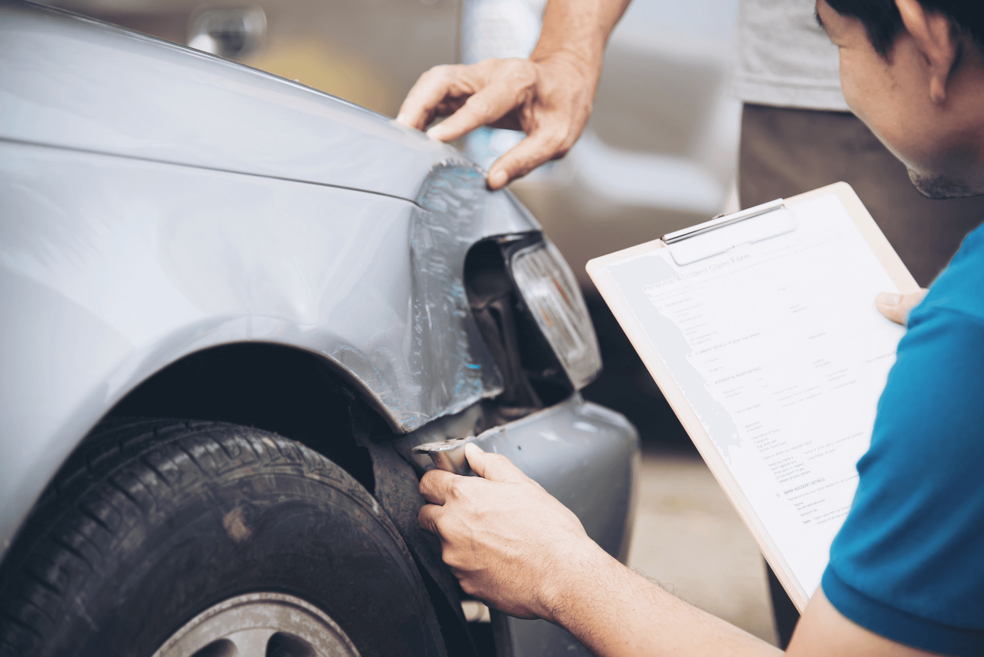 Person inspecting car damage after accident without insurance.