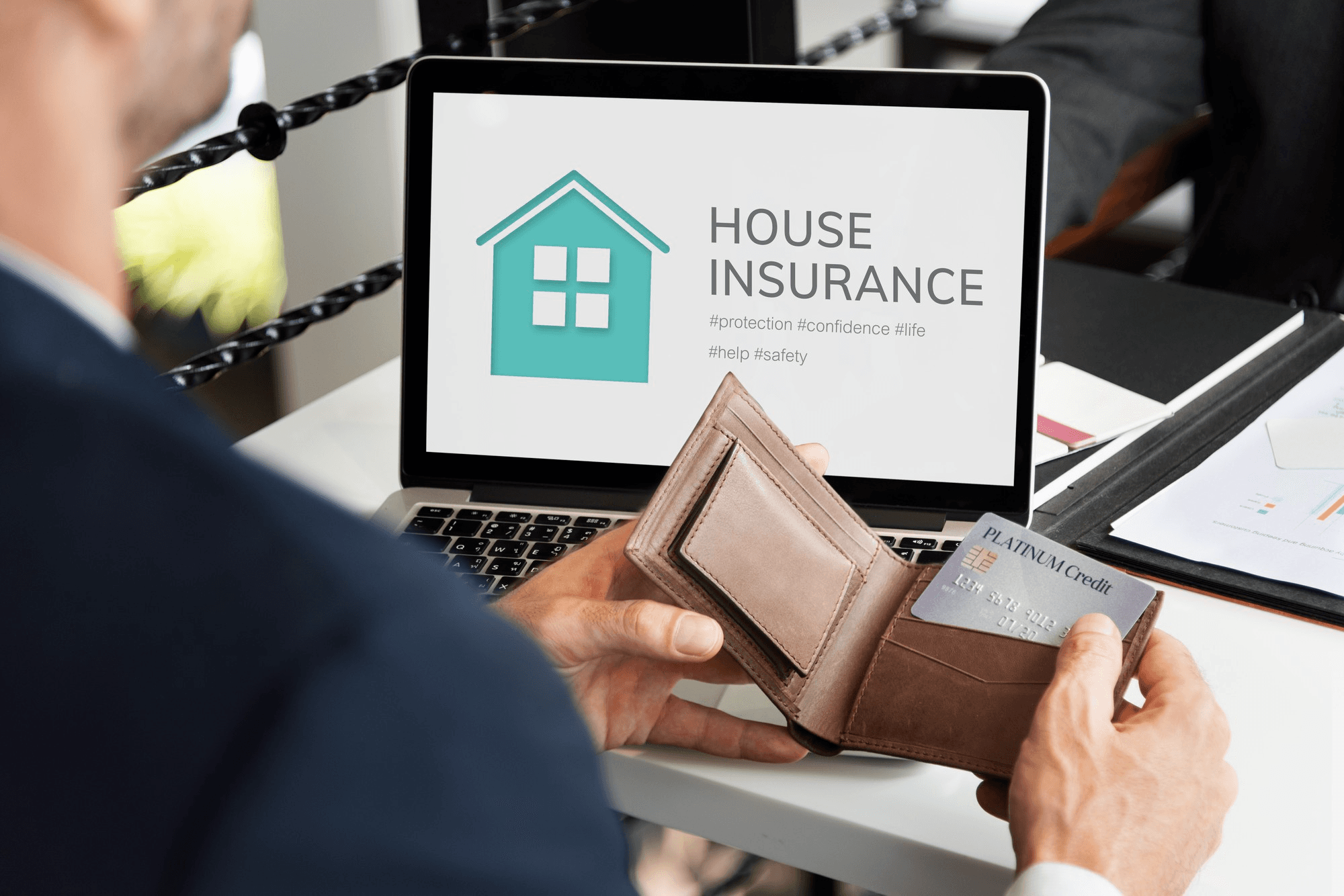 Man taking card from wallet while viewing home insurance online.