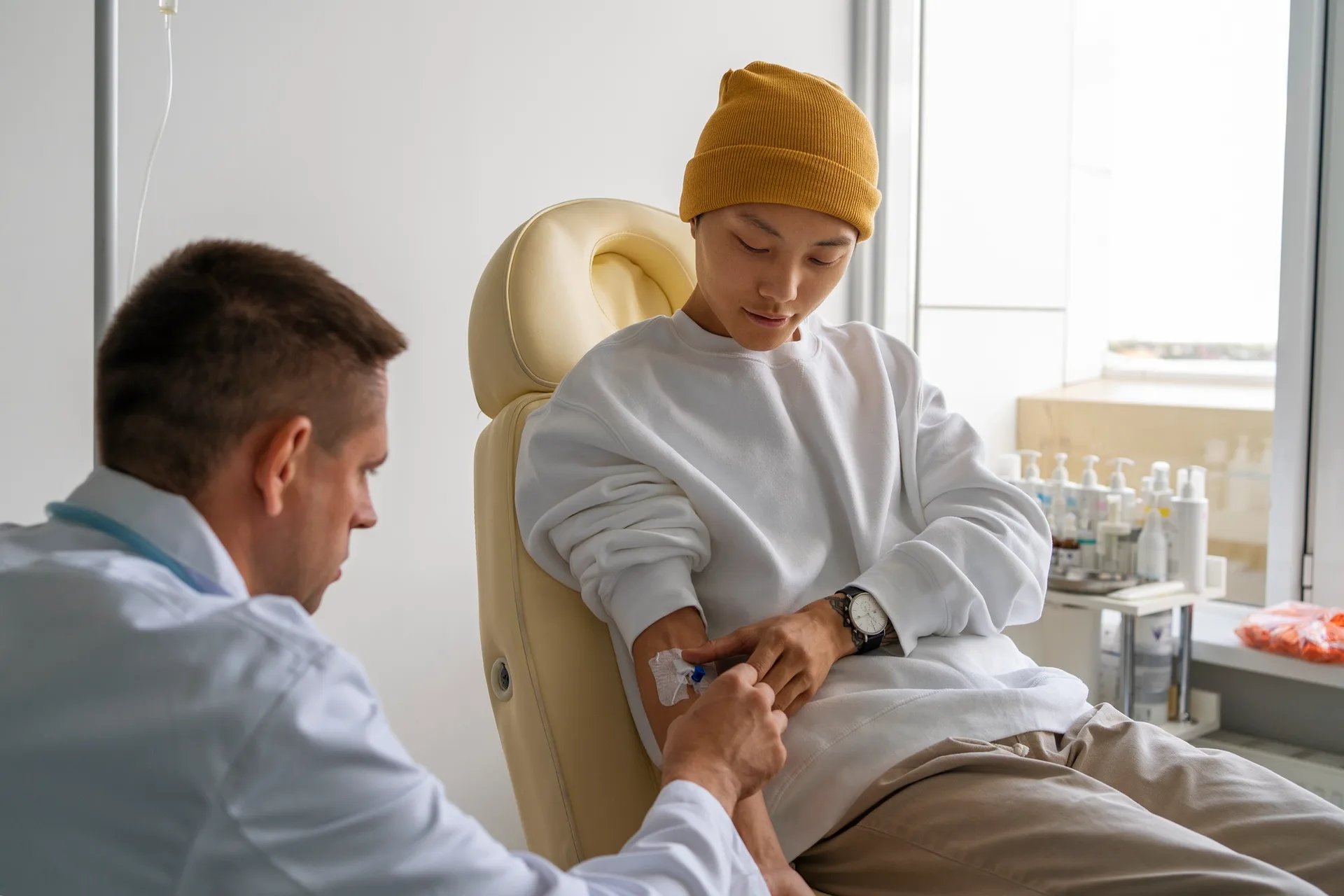 A cancer patient seated in a hospital chair receiving chemotherapy through an IV drip