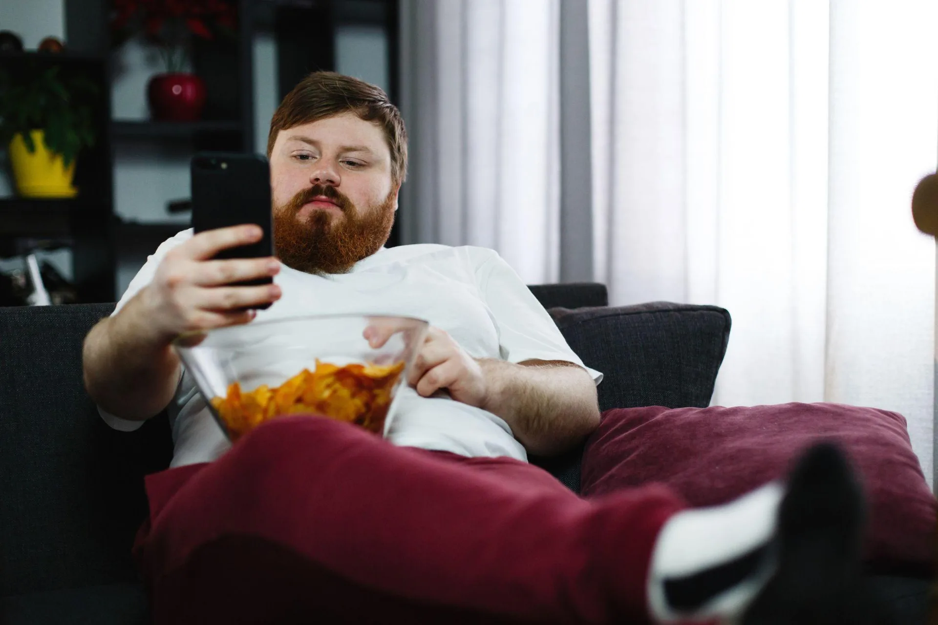 A man sitting on a sofa reading a suspicious message on his smartphone