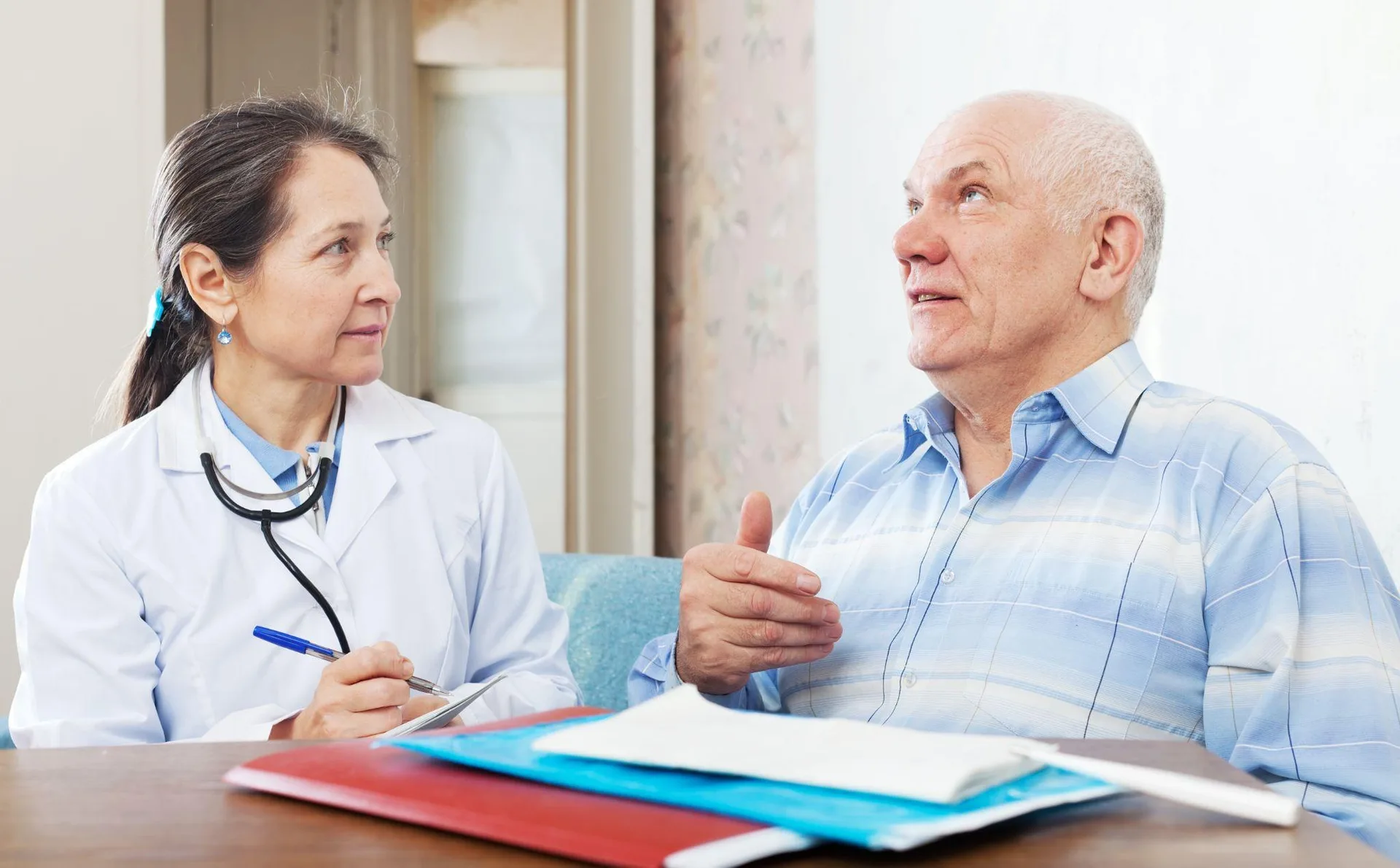 A doctor in a white coat reading an insurance policy document at a clinic desk